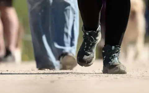 Wanderstiefel in Aktion, die den Boden aufwirbeln. Die boot geschwindigkeit ist spürbar, während die Wanderer voranschreiten.