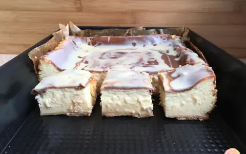 Pyszny sernik z polewą, pokrojony na kawałki. Czy do sernika dodaje się proszek do pieczenia? Ten wygląda idealnie!