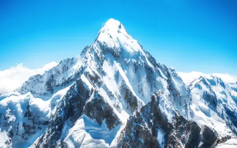 Majestatyczny szczyt pokryty śniegiem, symbolizujący ogromną mount everest wysokość. Błękitne niebo i chmury podkreślają jego potęgę.