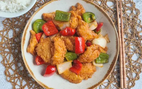 Delicioso pollo agridulce con pimientos rojos y verdes, y cebolla. Un plato vibrante y sabroso, listo para disfrutar.