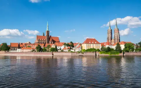 Widok na Ostrów Tumski we Wrocławiu, perłę Dolnego Śląska, z rzeką w tle.