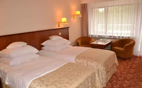 Przytulne hotel Gołębiewski pokoje z dwoma wygodnymi łóżkami, stolikiem i dwoma fotelami.