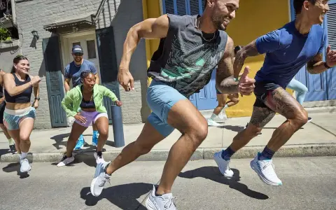 Grupa biegaczy w letnich strojach pokonuje miejską trasę. To inspiracja, jak przygotować się do maratonu, czerpiąc radość z ruchu.