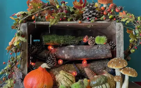 Décoration automne facile à faire : citrouilles, pommes de pin, guirlande de feuilles et champignons dans une caisse en bois.