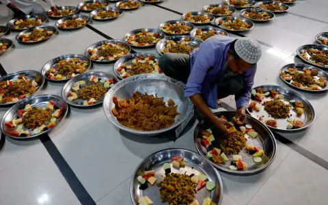 Männer bereiten Teller mit Essen und Obst für das Eid Fest vor.