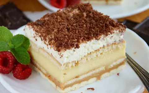 Pyszne ciasto 3 bit z kremem budyniowym, biszkoptami i bitą śmietaną, posypane czekoladą.