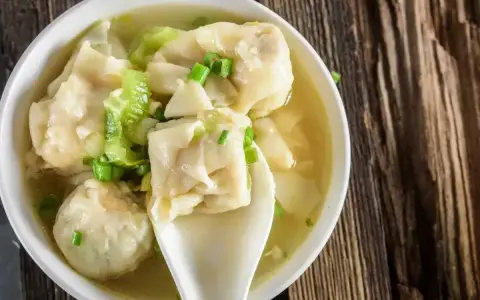Miseczka aromatycznej zupy z wontonami, gdzie delikatne ciasto do wontonów otula pyszne nadzienie. Posypana szczypiorkiem.