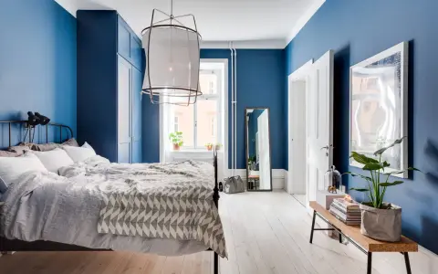 Accogliente camera da letto blu con letto comodo, armadio scuro e specchio a figura intera.