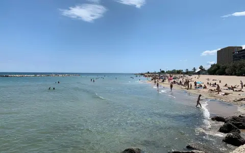 Sonniger bari strand mit vielen Menschen, die im Meer schwimmen und sich am Sand sonnen.