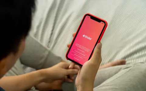 Osoba trzyma telefon z aplikacją Tinder. Zastanawiasz się, czy warto założyć Tindera? Może to początek nowej znajomości.
