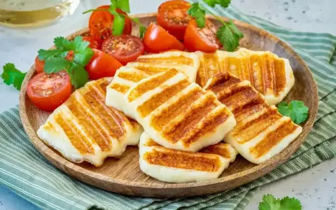 Grillowany ser halloumi z pomidorkami koktajlowymi i kolendrą. Idealny pomysł, co zrobić z sera halloumi na lekki posiłek.