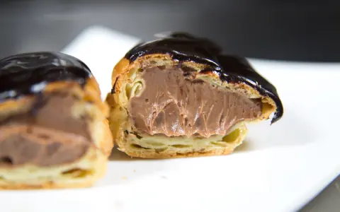 Éclairs généreusement garnis de crème pâtissière chocolat, nappés d'un glaçage brillant. Un délice gourmand.