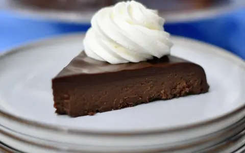 En bit fransk chokladtårta med en virvel av vispad grädde på en tallrik.
