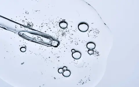 Kropla serum z pipetką, pełna pęcherzyków powietrza. Czy peptydy można łączyć z witaminą C? To pytanie nurtuje wiele osób dbających o cerę.