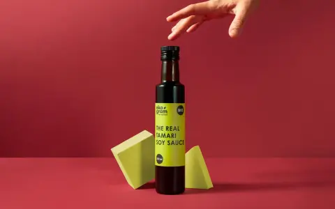 Butelka sosu tamari z etykietą "THE REAL TAMARI SOY SAUCE" na tle.