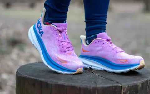Fioletowe buty Hoka Clifton na pniu drzewa. Hoka to firma znana z amortyzacji.