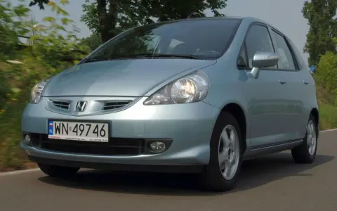 Jasnoniebieski Honda Jazz 2 na drodze, z zielenią w tle.