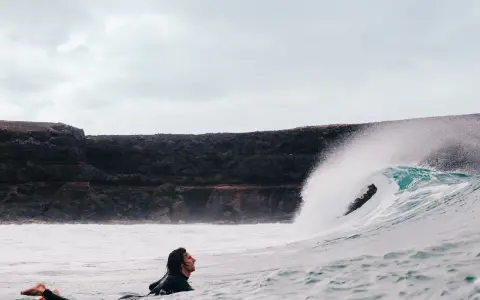 Surfer wartet auf die perfekte Welle vor einer Felswand, um Costa Calma surfen zu gehen.
