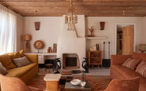 Ambiance chaleureuse dans cet **intérieur maison île de Ré**. Canapés confortables, cheminée imposante et plafond en bois créent un cocon douillet.