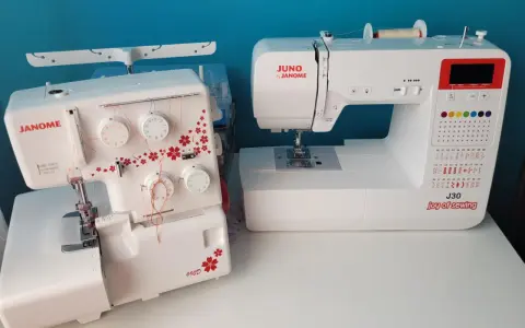 Dwie maszyny do szycia: biały owerlok Janome 990d z czerwonymi kwiatami i biała maszyna Juno by Janome J30.