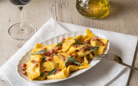 Piatto di casoncelli alla bergamasca conditi con burro, salvia e pancetta croccante.