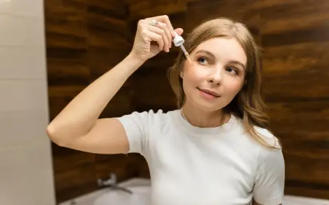 Donna applica siero viso con contagocce, concentrandosi sul giusto retinolo percentuale per la sua pelle.