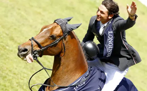 Un cavalier, Nino des Buissonnets, salue la foule depuis son cheval après une compétition.