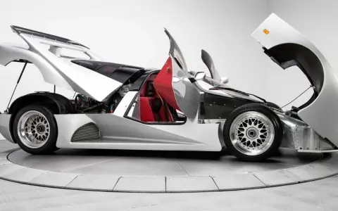 Silberner Lotec C1000 Supersportwagen mit geöffneten Türen und Hauben, rote Sitze und sichtbarer Motor.