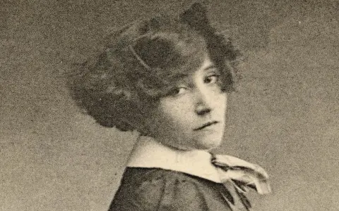 Portrait de Colette jeune, regardant par-dessus son épaule, avec une coiffure bouclée et un col blanc.
