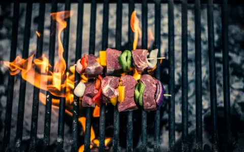 Brochetas de carne y verduras sobre parrilla de carbón, llamas naranjas. ¡Así se hace barbacoa carbón!