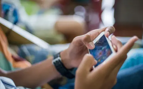 Ręce trzymające smartfon, grające w grę. Czy to przykład phubbing co to znaczy? Ignorowanie otoczenia dla telefonu.