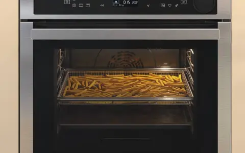 Horno con una bandeja llena de patatas fritas en su interior.