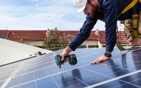 Instalator fotowoltaiki montuje panele na dachu. Szkolenie dla przyszłych fachowców.