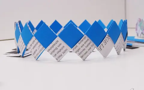 Eine selbstgebastelte Geburtstagskrone aus Papierstreifen, blau und weiß, mit Text bedruckt. Perfekt zum Geburtstagskrone basteln!