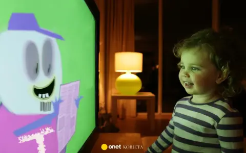 Mała dziewczynka z zaciekawieniem ogląda na ekranie telewizora krótkie filmy dla dzieci z zabawną postacią.