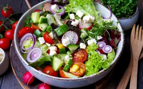Ein bunter gemischter Salat mit Tomaten, Gurken, Radieschen, Zwiebeln und Feta.