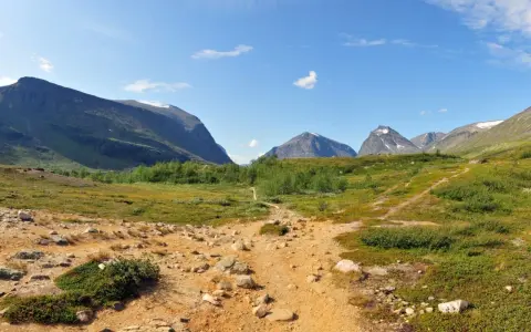 Vandringsled mot Kebnekaise, en fantastisk utsikt som gör bestiga Kebnekaise pris värt. Berg, grönska och en klarblå himmel.