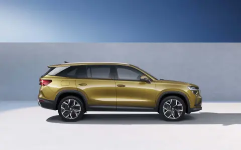 Złoty skoda suv z nowoczesnymi felgami stoi na tle niebieskiego nieba i szarej ściany.