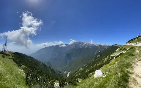 Panoramica mozzafiato sui monti dell'Abruzzo, con un sentiero che sale verso un **block house** e torri di trasmissione.