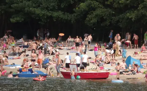 Tłum ludzi odpoczywa na plaży nad jeziorem w Jelczu Laskowicach. Słońce, piasek i woda tworzą idealne warunki do letniego relaksu.