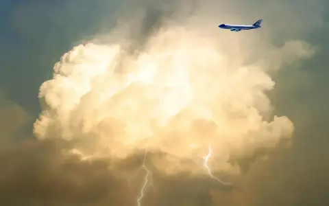 Samolot leci obok burzowej chmury z błyskawicami. To pokazuje, co to są turbulencje.