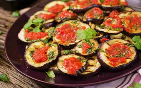 Fette di melanzane grigliate condite con salsa di pomodoro e basilico, un gustoso piatto di melanzane alla pizzaiola.