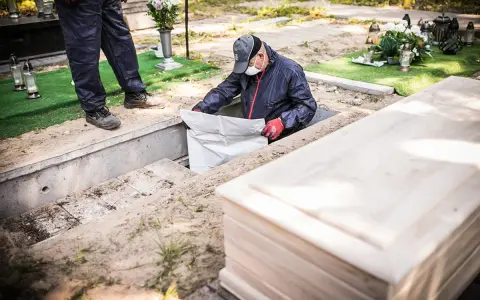 Pracownicy przygotowują ekshumację po 30 latach. Widać trumnę i koparkę.