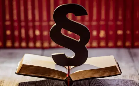 Symbol paragrafu na otwartej księdze, sugerujący karę finansową dla pracownika. W tle rząd czerwonych ksiąg.