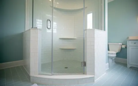 Salle de bain avec carrelage bleu pâle et une douche d'angle. Ce receveur de douche à éviter, avec ses étagères peu pratiques, est un cauchemar à nettoyer.