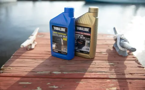 Deux bidons d'huile Yamalube pour moteur 4 temps, l'un bleu (10W-30) et l'autre doré (5W-30), sur un ponton en bois.
