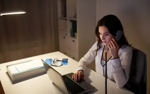 Młoda kobieta, dyspozytor, pracuje po godzinach przy laptopie i telefonie.