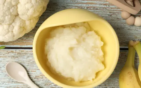 Puré de coliflor listo para servir. Ideas de recetas de coliflor para niños, con plátanos y cuchara.