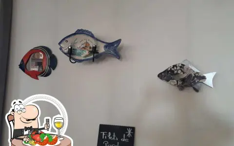 Décoration murale en forme de poisson au restaurant Le Saint Pierre La Tronche. Assiette de fruits de mer et verre de vin.