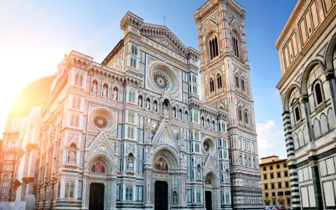 La majestueuse coupole de Florence, le Duomo, se dresse fièrement sous un ciel bleu, baignée par les rayons du soleil.